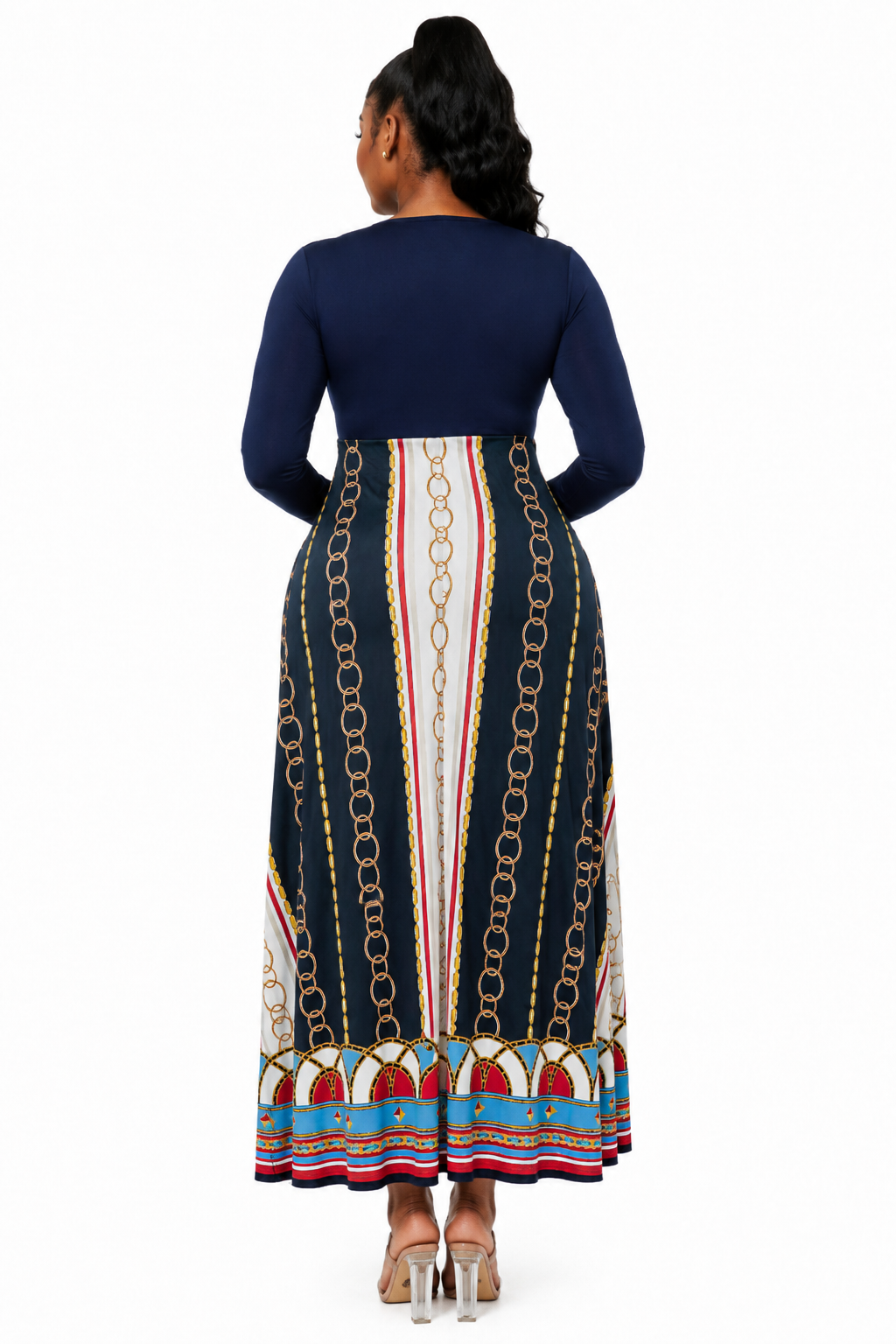 A woman shown from the back wearing a long-sleeve maxi dress with a navy blue top and a multicolor skirt featuring vertical chain-link patterns and striped details.