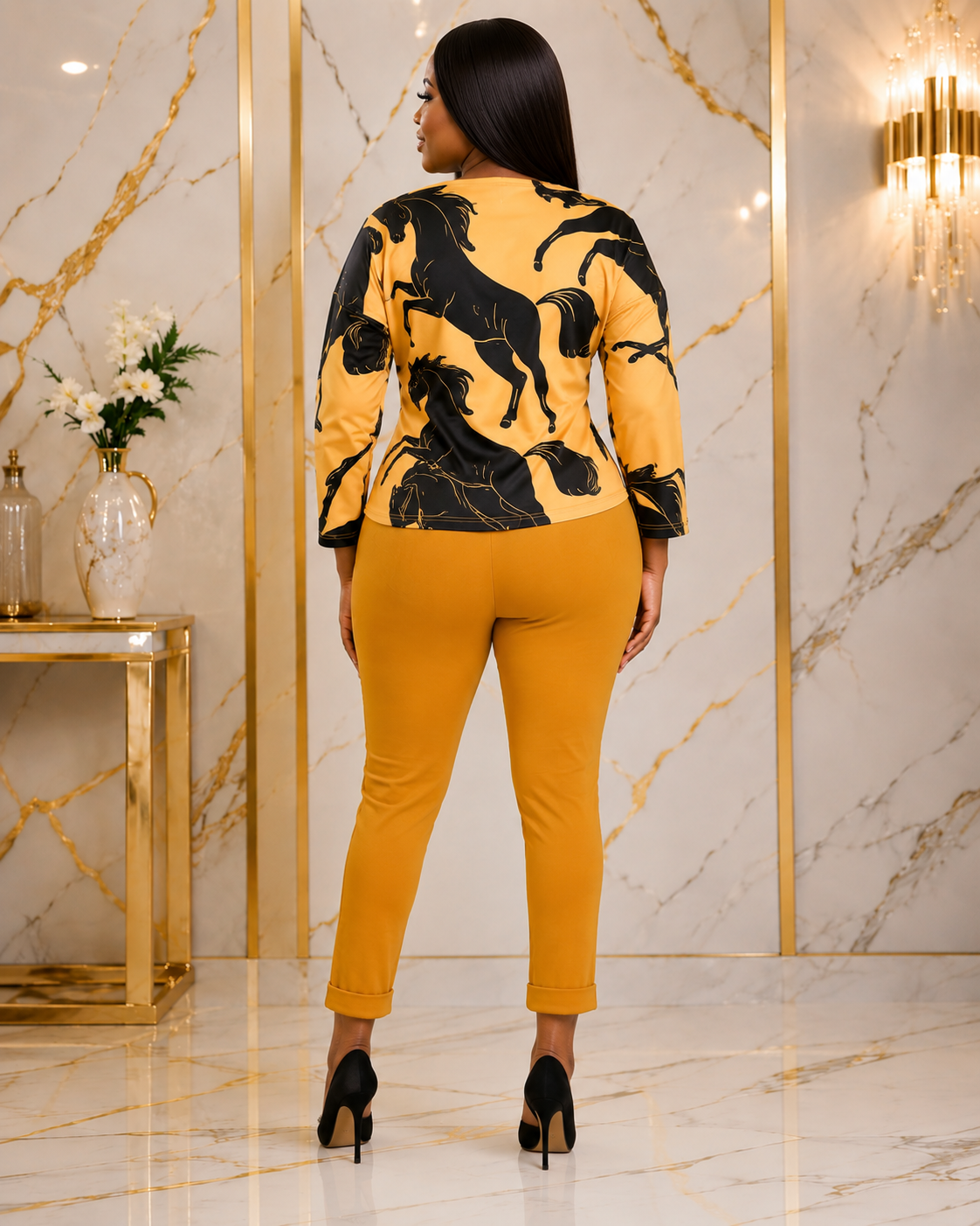 A woman shown from the back wearing a mustard yellow and black horse-patterned long-sleeve top with matching mustard yellow cropped pants and black heels, standing in a luxury interior with marble walls and gold trim.