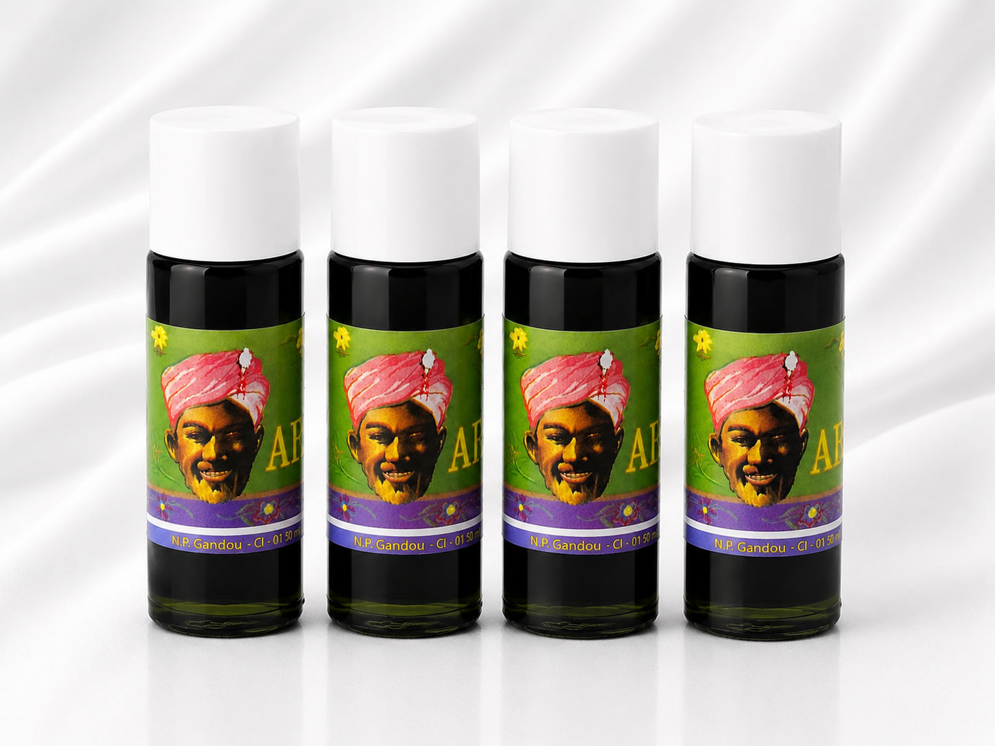 Four small cylindrical bottles with white caps and dark bodies, arranged in a row on a white satin-like background. Each bottle has a colorful label featuring a stylized portrait of a man in a pink turban and the text 'AF.