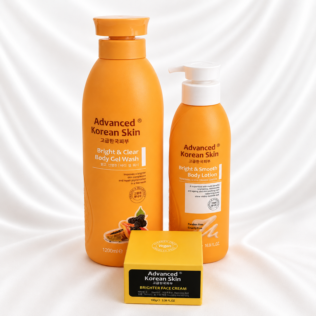 A three-piece skincare set from Advanced Korean Skin for Bright & Clear Body Gel Wash, Bright & Smooth Body Lotion, and Brighten Face Cream, displayed on a white satin fabric background.