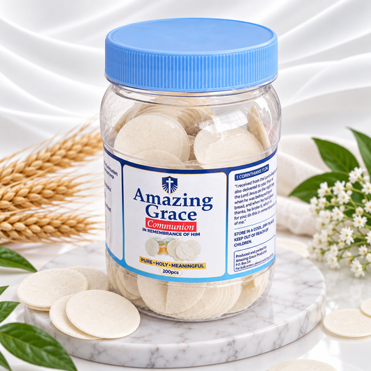 A clear plastic jar of Amazing Grace Communion with a blue lid, filled with round communion wafers, displayed on a marble slab with wheat and green leaves.