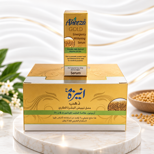 A boxed skincare product labeled 'Areeza Gold Emergency Whitening Serum' stands behind a larger matching outer box on a white marble pedestal. The packaging is predominantly gold with green bands and Arabic text, with a small bowl of yellow seeds and white flowers in the softly blurred background.