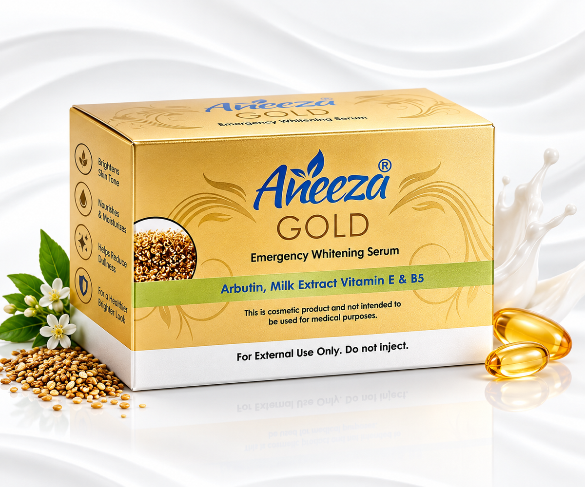 A box of Aineeza Gold Emergency Whitening Serum shown on a white liquid background with decorative seeds, flowers, and two gold capsules. The box is gold and white with blue and green text.
