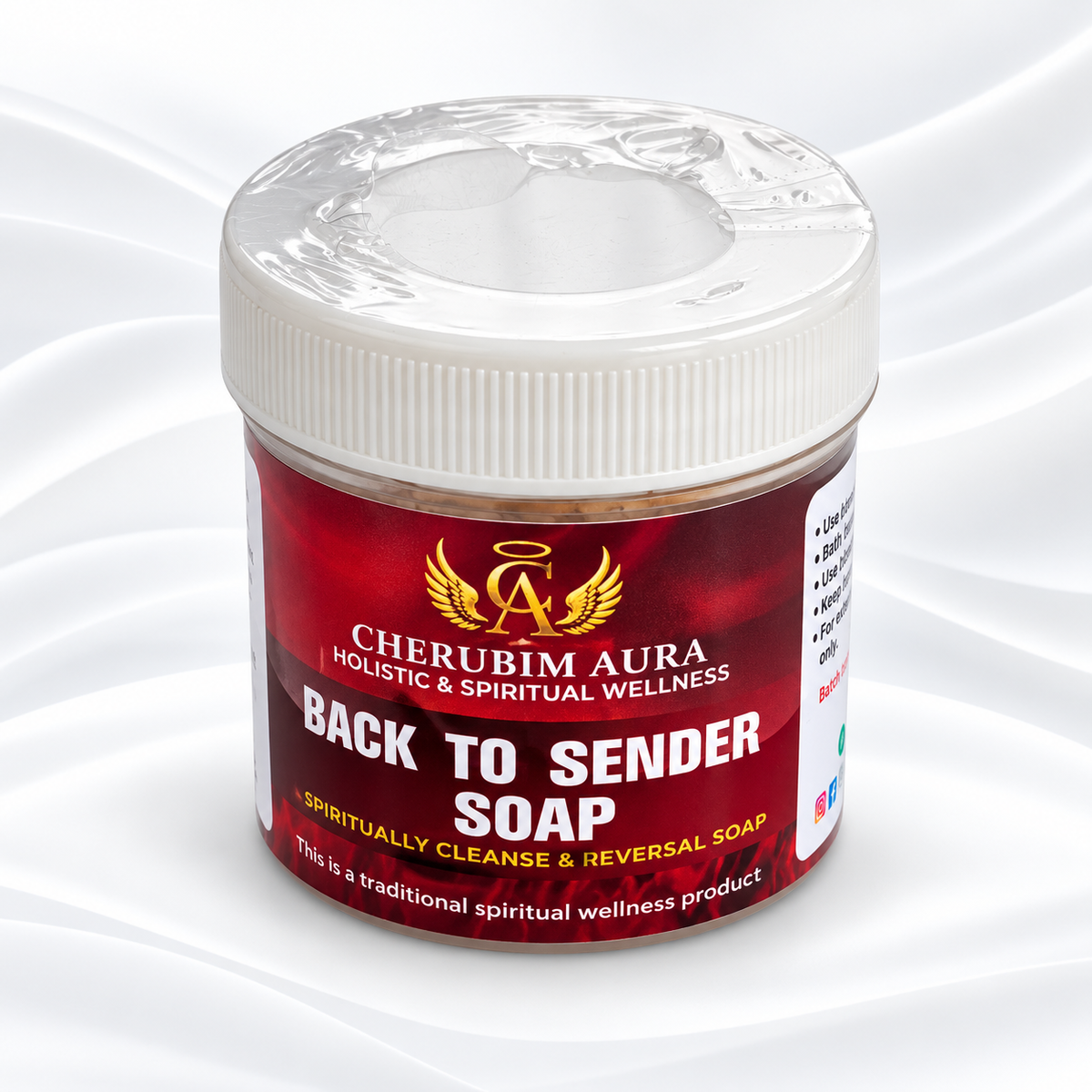 A jar of Cherubim Aura Back to Sender Soap on a white satin-like background. The product is in a clear plastic jar with a white screw cap and a red label featuring gold and white text.