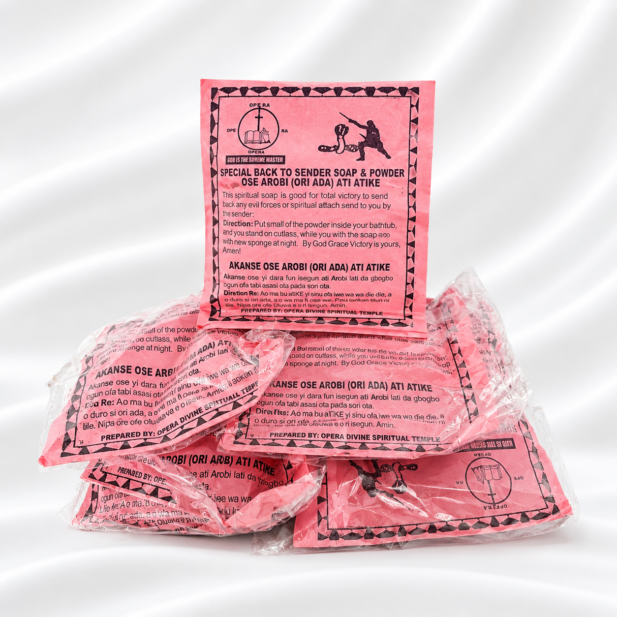 Pink ritual soap and powder packets with printed red and black labels, arranged on a white studio background.