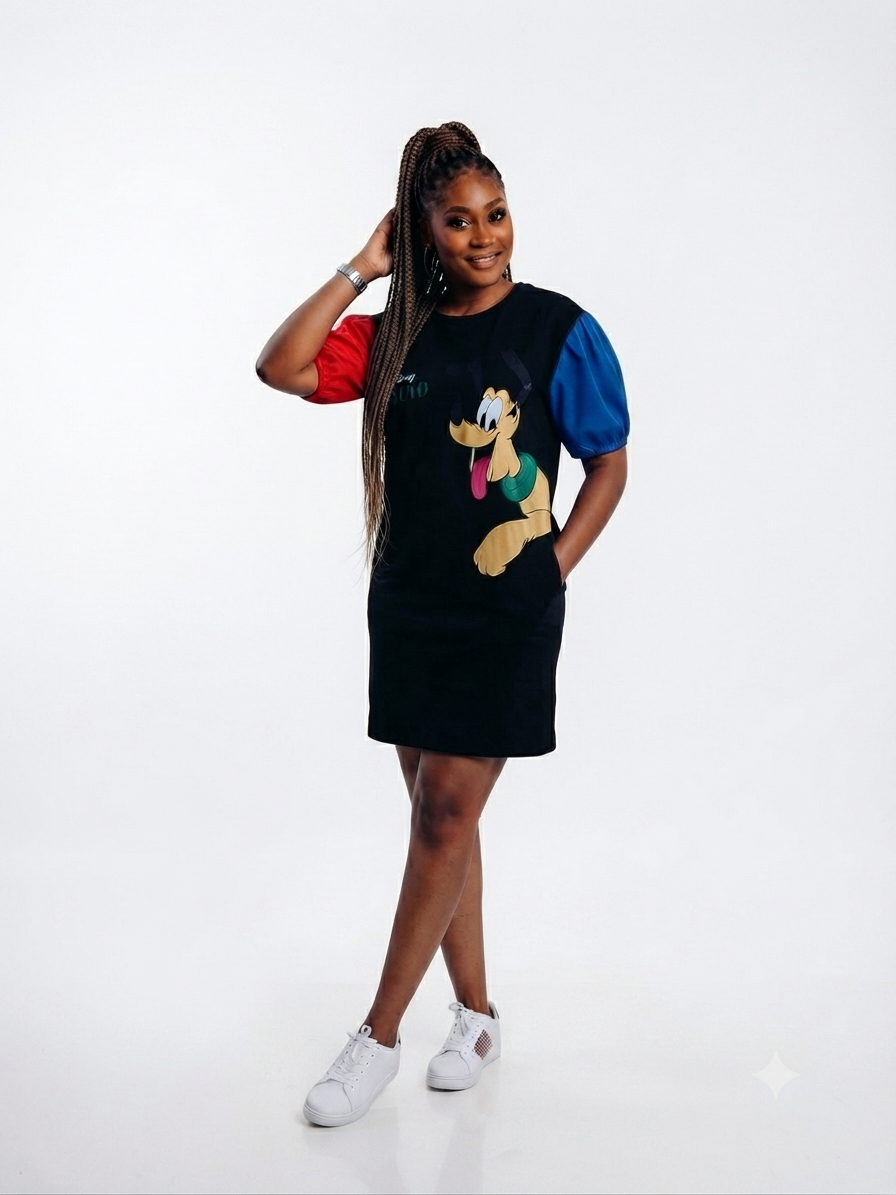 A woman modeling a black mini dress with a large cartoon dog graphic on the front, featuring red and blue puff sleeves, paired with white sneakers, against a plain white studio background.