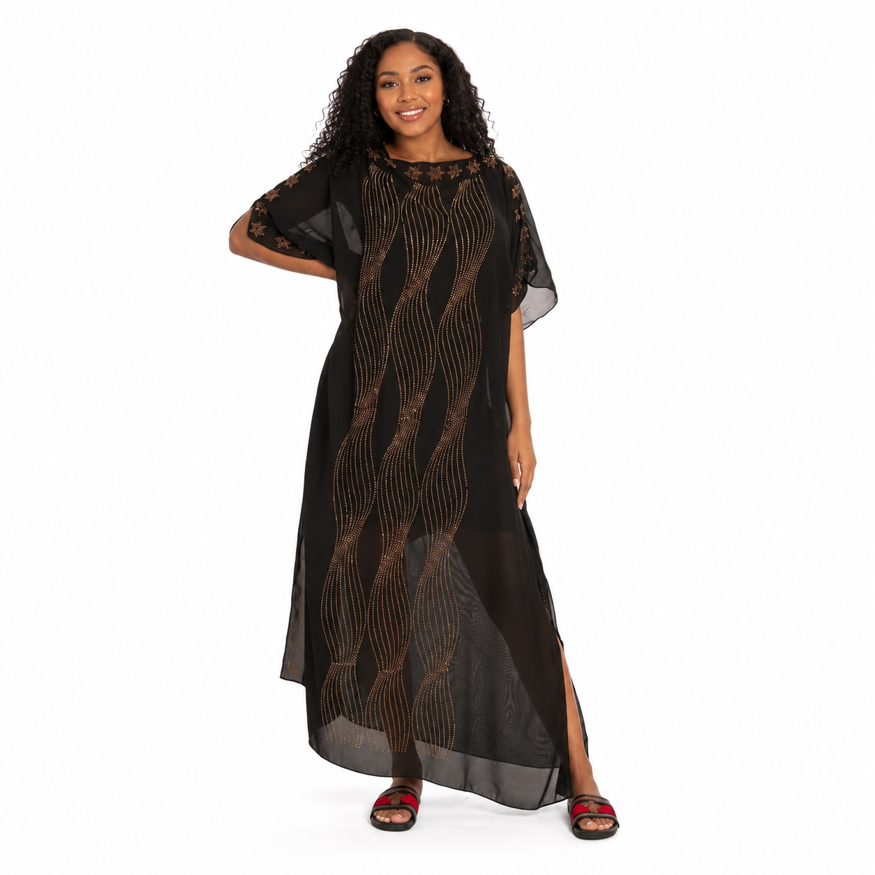 A woman modeling a black sheer maxi dress with brown wavy line patterns, featuring short wide sleeves and a side slit, set against a plain white background.