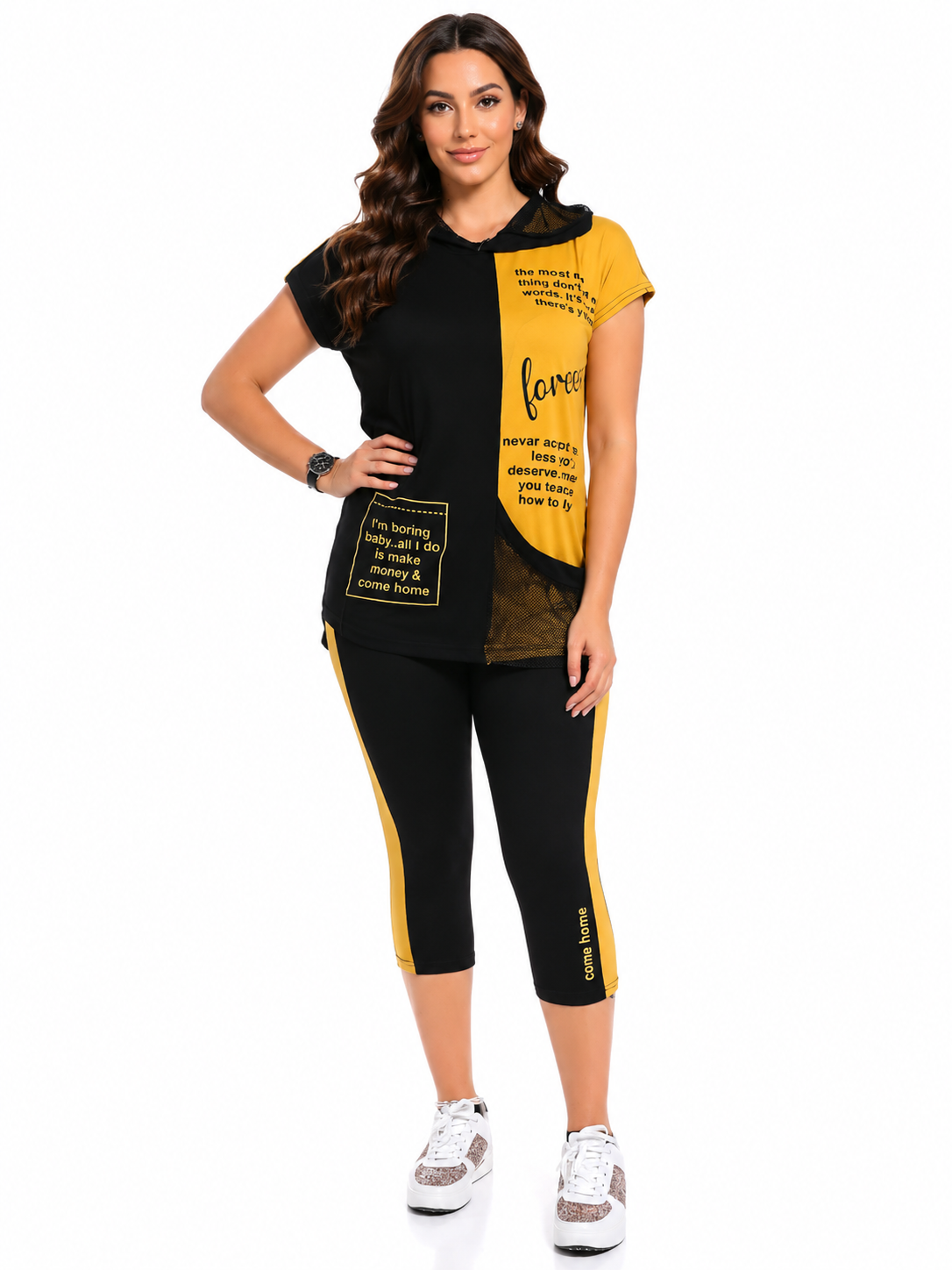 A woman modeling a matching black and yellow color-blocked activewear set featuring a short-sleeve top with text graphics and matching capri leggings with yellow side panels, set against a plain white background.