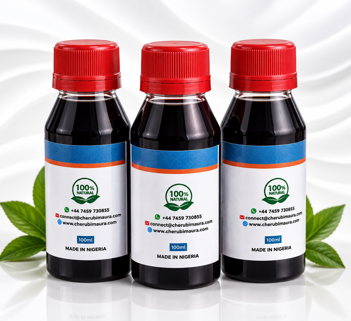 Three small plastic bottles of dark liquid with red caps and white labels, arranged side by side on a glossy white surface with green leaves at the sides. The labels show a circular '100% Natural' logo and text including 'MADE IN NIGERIA' and '100ml'.