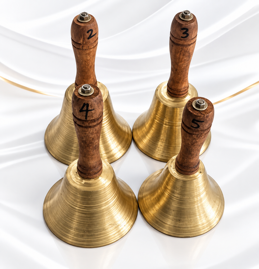 Four brass bells with wooden handles numbered 2 through 5, arranged on a white draped fabric background.