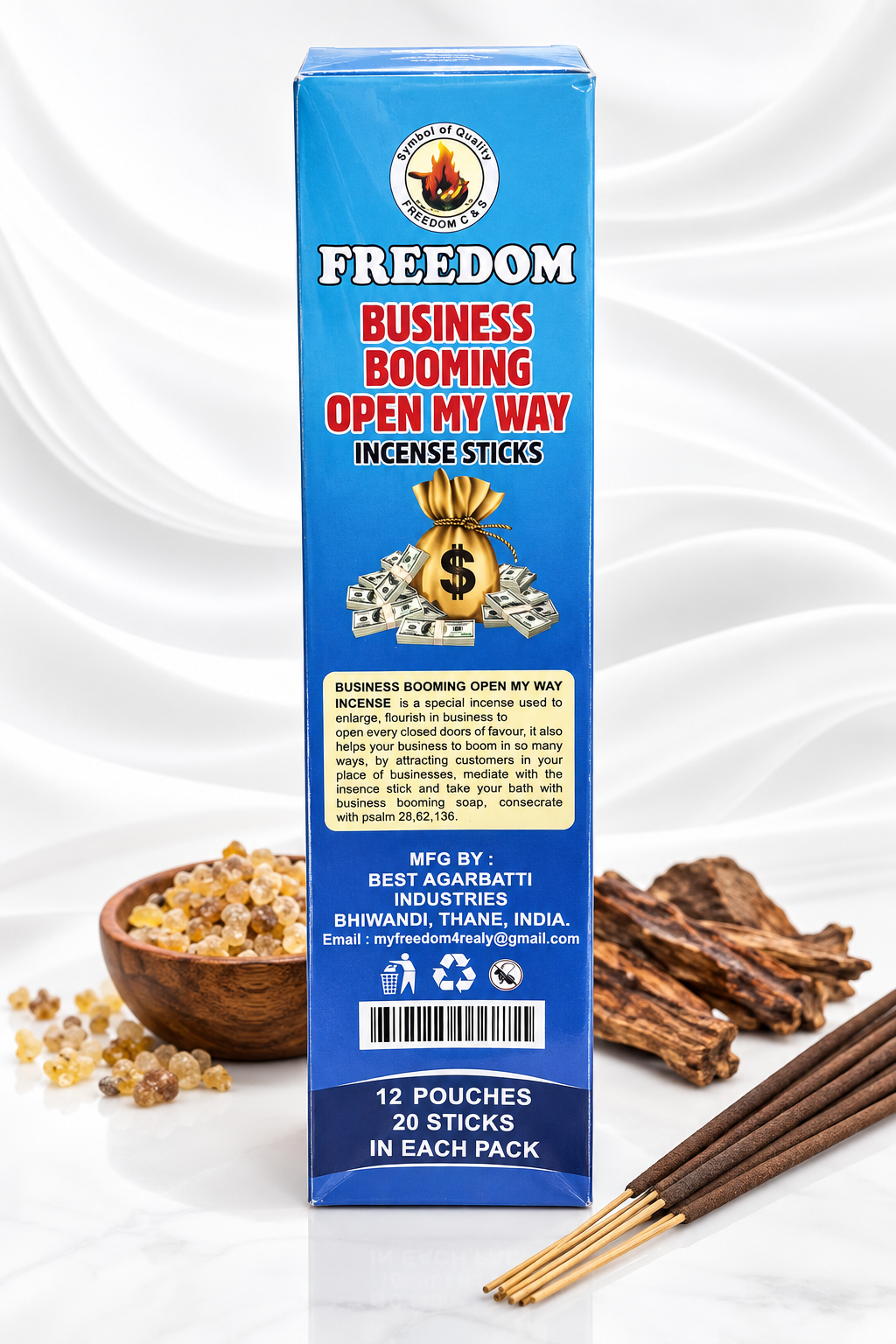 A blue rectangular box of Freedom Business Booming Open My Way incense sticks, shown upright on a white surface with a few incense sticks and a small bowl of incense pieces in front. The box has red, yellow, and white text and graphics, including a money bag illustration.