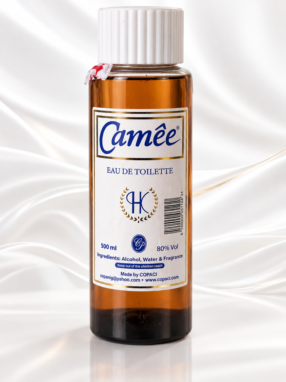 A 500 ml bottle of Camée Eau de Toilette by CRPADI, featuring an amber brown glass bottle, a white ribbed cap, and a white label with blue and gold text, set against a white satin fabric background.