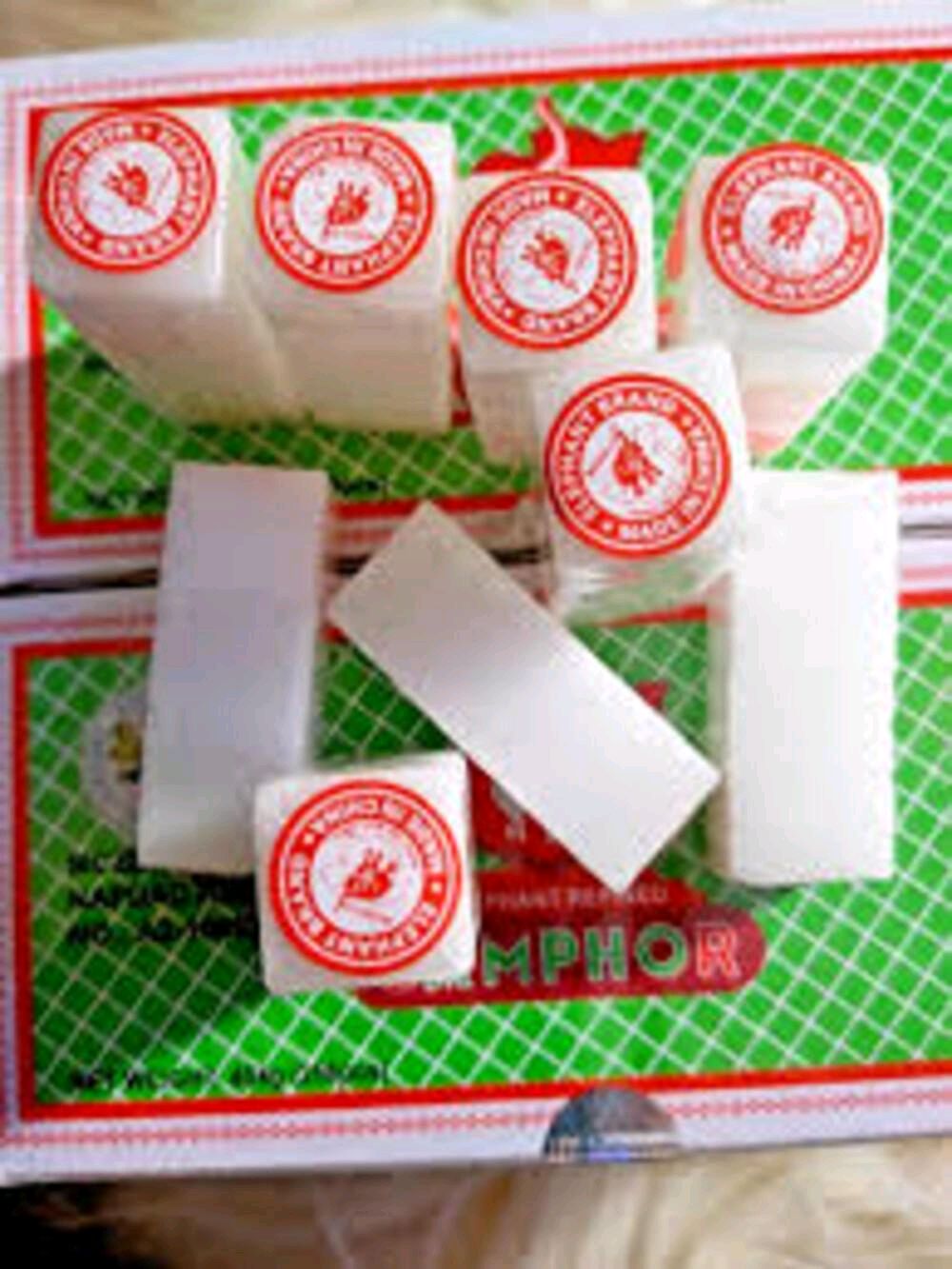 White rectangular blocks of castor oil resin wax with red circular labels, arranged on top of a green and white patterned box labeled 'SMPHOR'.