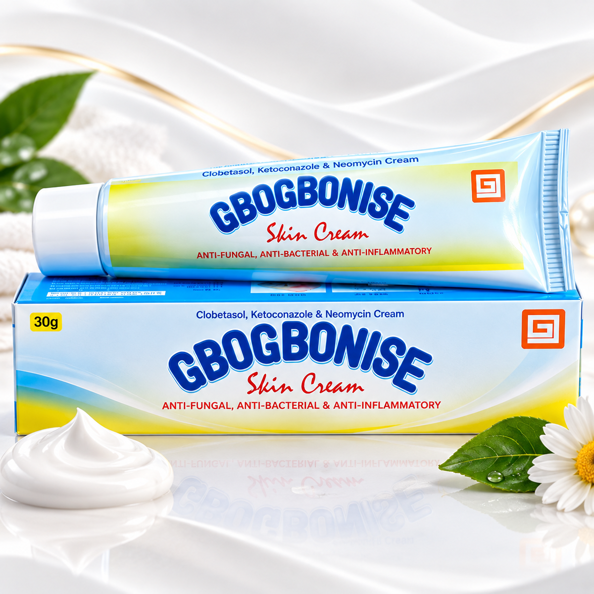 A tube and box of GBOGBONISE Skin Cream stacked together on a white surface, with a dollop of white cream in front, green leaves, and a daisy flower around the product. The packaging is light blue and yellow with bold blue and red text.