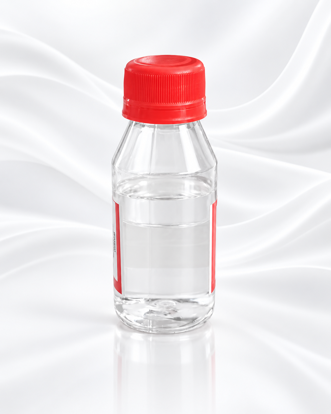A clear plastic bottle filled with transparent liquid, featuring a bright red screw cap and a matching red label, set against a white satin-like draped background.