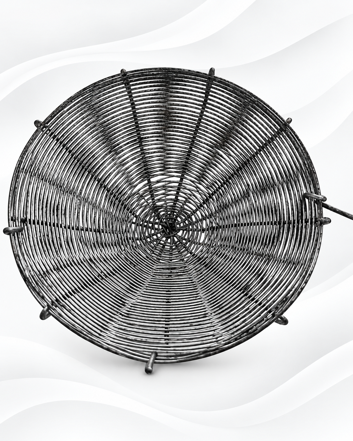 A round black metal wire rack or spiderweb-style decorative screen with radial wire patterns, shown against a white background with soft gray wavy lines.