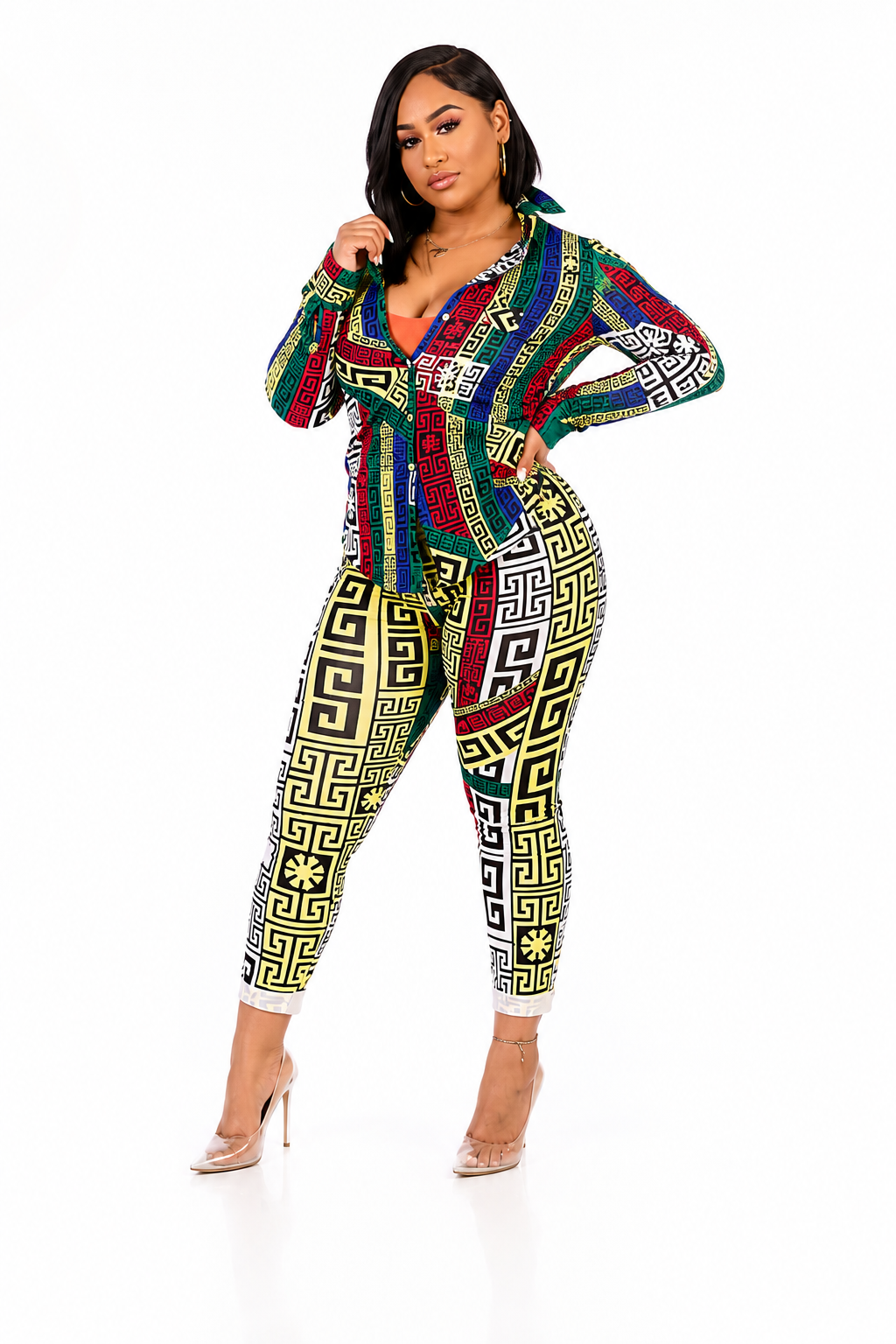 A woman modeling a matching two-piece set featuring a long-sleeve button-up shirt and high-waisted leggings with a colorful Greek key pattern in red, green, yellow, black, and white, posed against a plain white background.