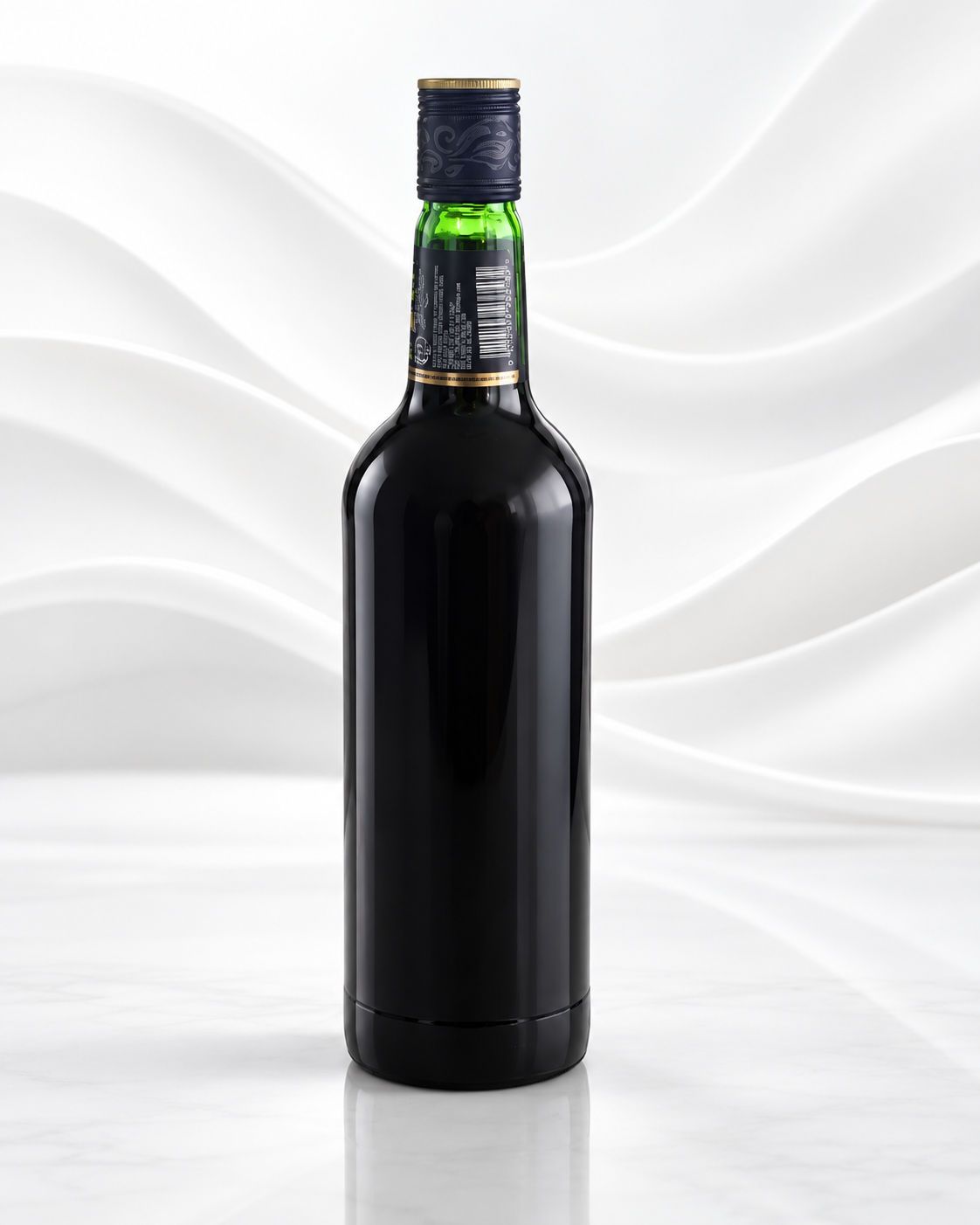 A single dark glass bottle with a black body, gold neck band, green glass neck section, and dark cap, centered on a white wavy studio background.