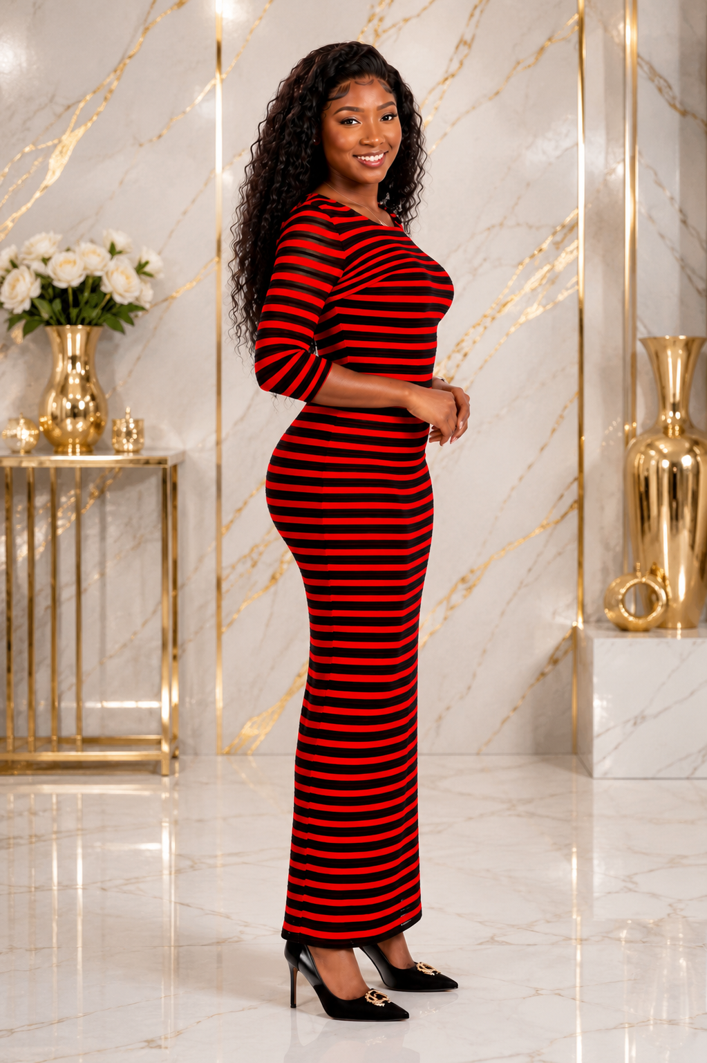 A woman modeling a red and black horizontally striped long-sleeve maxi dress in a luxurious interior with gold accents and marble floors.