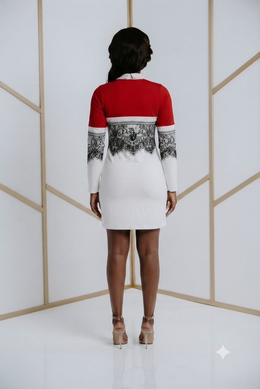 A woman viewed from behind wearing a long-sleeve mini dress with a red upper back, black and white ornate patterned yoke, and a white skirt, standing in a bright studio with geometric gold lines on a white wall.