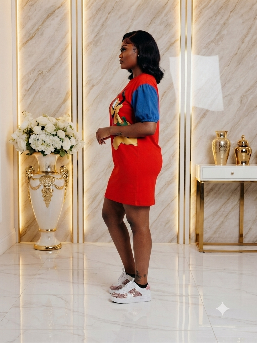 A woman stands in profile wearing a bright red mini dress with blue short sleeves and a colorful graphic print on the front, paired with white sneakers, set against a luxury marble interior with gold accents.