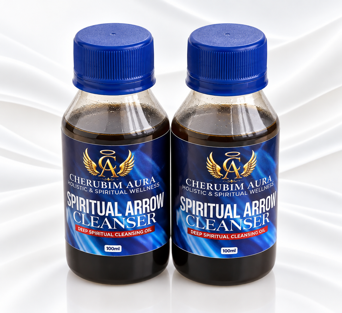 Two 100ml bottles of Cherubim Aura Spiritual Arrow Cleanser oil, displayed side-by-side on a white satin fabric background.