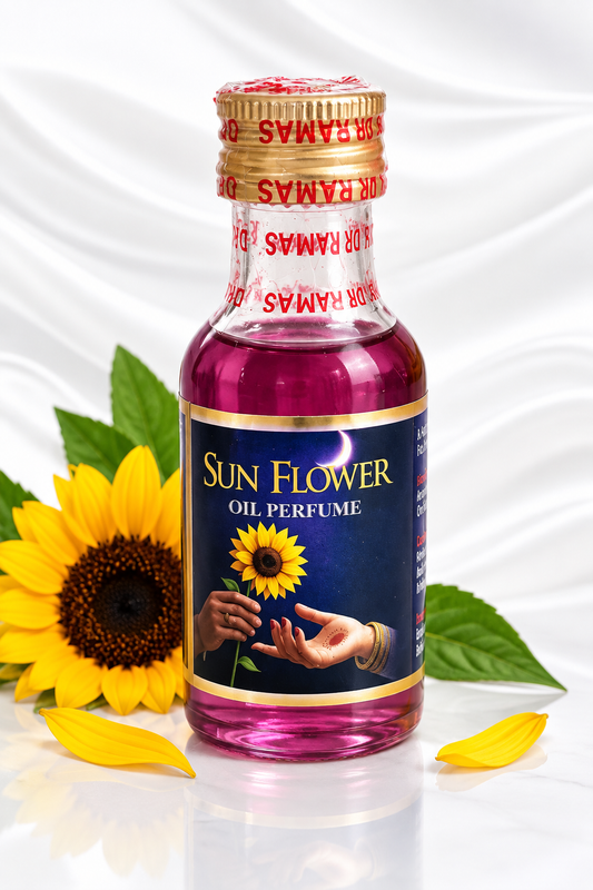 A bottle of Ramas Sun Flower Oil Perfume with a dark blue label and gold accents, filled with pink liquid. The bottle is styled with a yellow sunflower, green leaves, and yellow petals on a white draped satin background.