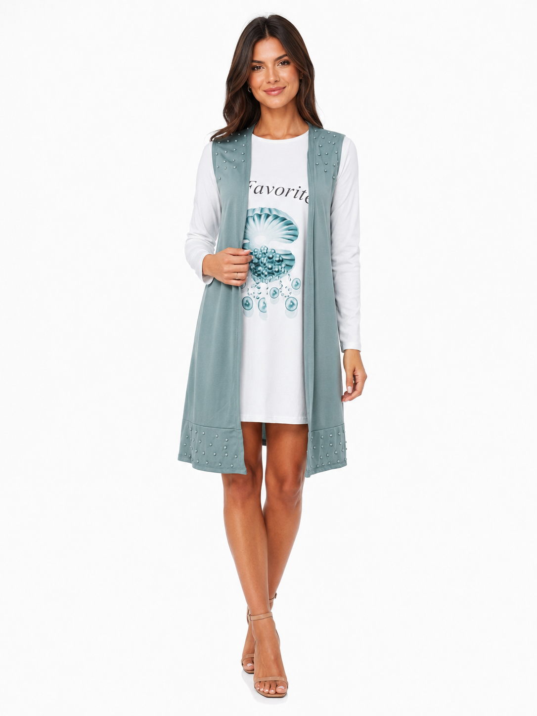 A woman modeling a long, sleeveless, open-front sage green vest over a white long-sleeve t-shirt with a blue graphic print, set against a plain white background.