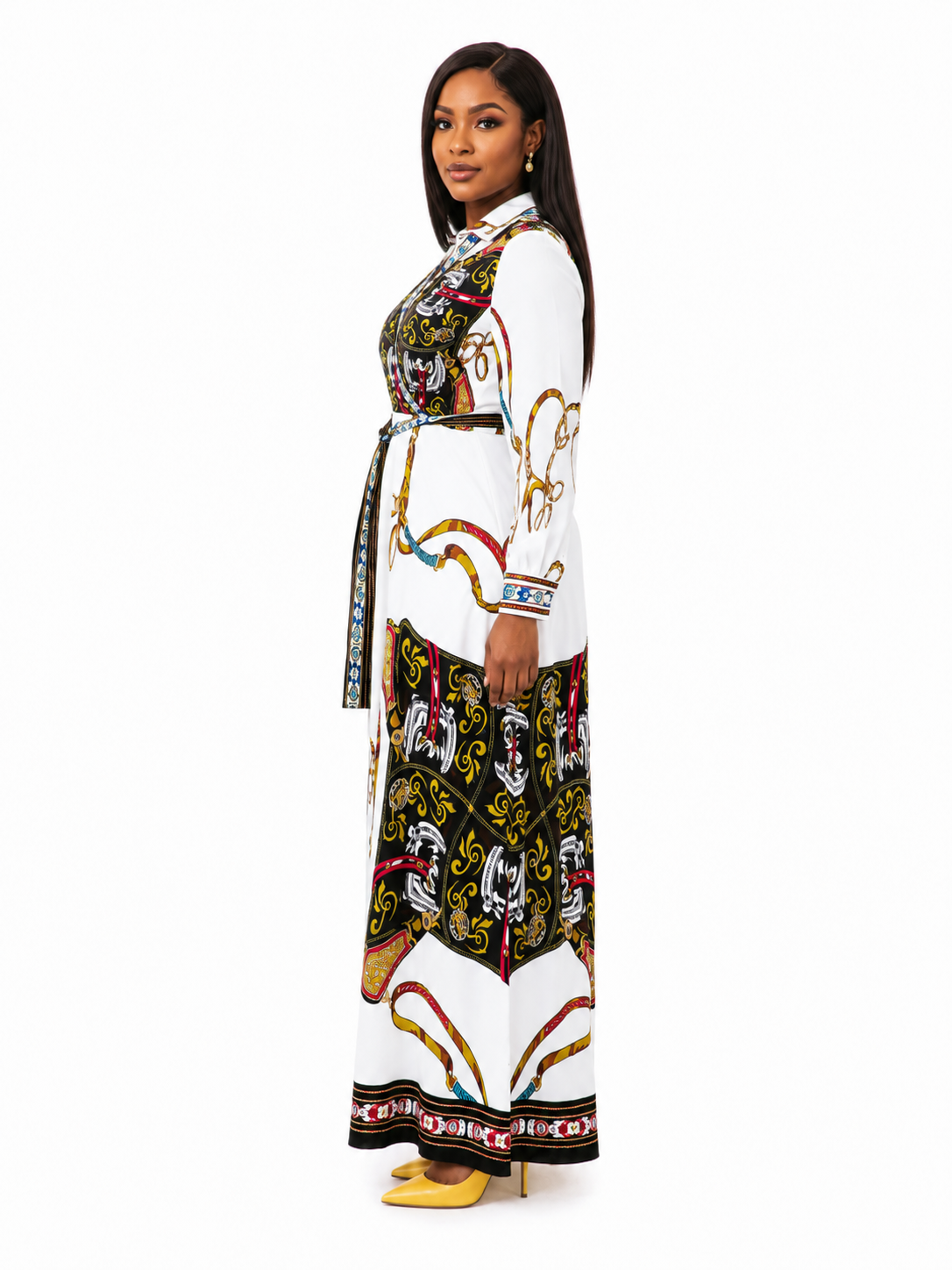 A woman modeling a long white maxi dress with a colorful abstract print and a matching tie belt, shown in profile against a plain white background.